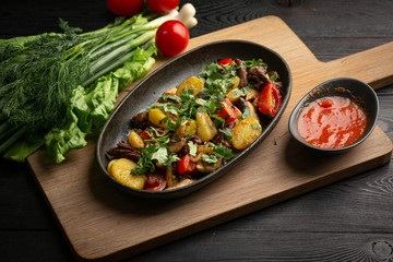 roast beef in a black oval plate on a wooden board on a dark background