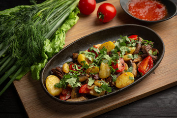 roast beef in a black oval plate on a wooden board on a dark background