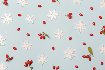 Christmas pattern made of snowflakes and red berries on pale blue background. Christmas, winter holiday, new year concept. 