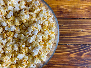 Popcorn in glass bowl on wooden background