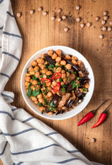 Hot spicy chickpeas stewed with vegetables in a white bowl on a wooden background, top view, free space for text. Healthy vegetarian food.