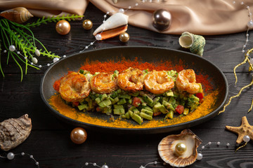tartar shrimp with avocado and spices on a black oval plate