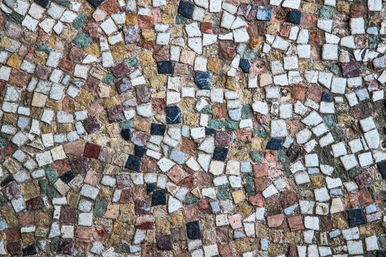 Close up on old worn and weathered Ancient mosaic tiles design on the ground 