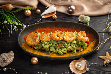 tartar shrimp with avocado and spices on a black oval plate
