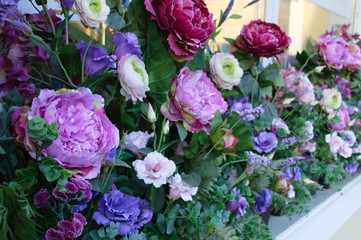 Purple peonies blooms in the summer on the windowsill from the facade of the house.