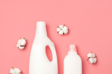 Eco cleaning concept. White plastic packaging of laundry detergent, liquid powder, washing conditioner and cotton flowers on pink background. Flat lay top view copy space. Bio organic product