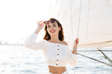 Emotional pretty woman outdoors posing on yacht in sea.