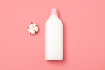 Eco cleaning concept. White plastic packaging of laundry detergent, liquid powder, washing conditioner and cotton flowers on pink background. Flat lay top view copy space. Bio organic product