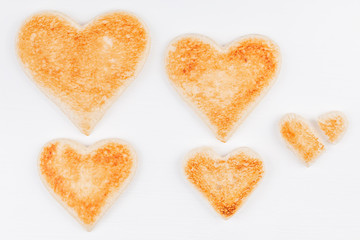 Obraz na płótnie Canvas Group of toasted bread hearts with one broken heart together on white background. The concept of unhappy and misunderstanding in big family.