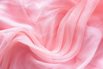 Delicate pink organza chiffon fabric background with swirl creased texture. Sewing fashion clothes...