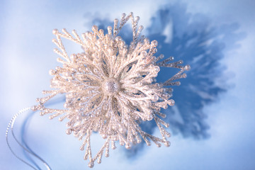 Silver sparkling snowflake on blue background close up, festive concept