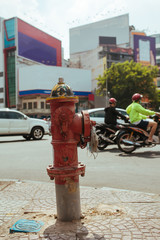 Fototapeta na wymiar Old red Fire Hydrant on the street in Vietnam