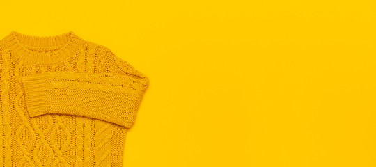 Autumn flat lay composition. Orange yellow knitted woolen female sweater on yellow background top...