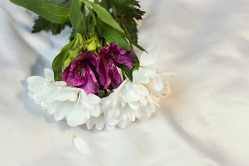 Purple  cute gentle lilac irises and white chamomile herbers flowers lie on a silver gray sheet on  bed  top view, romantic flat lay