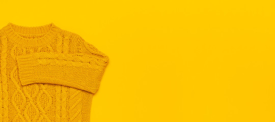 Autumn flat lay composition. Orange yellow knitted woolen female sweater on yellow background top view copy space. Fashionable women's fall winter accessories. Cozy Knit Jumper Stylish Lady Clothes