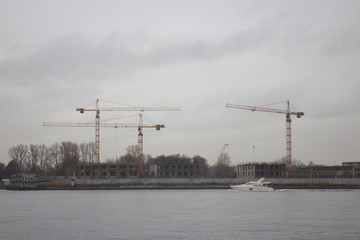 Obraz premium tower cranes on the shore on a cloudy day