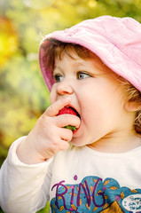 pretty little girl biting into a juicy strawberry