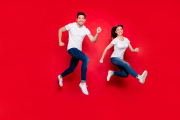 Fototapeta na wymiar Turned full length body size photo of cheerful cute nice pretty girlfriend boyfriend spouses wearing jeans denim white t-shirt footwear smiling toothily running jumping isolated vivid color background