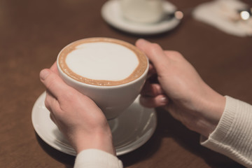 young woman holding a cup of cappuccino