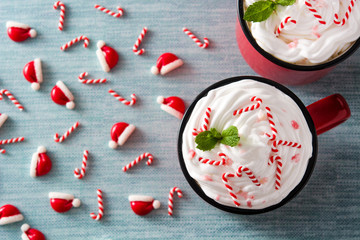 Peppermint coffee mocha decorated with candy canes for Christmas on blue background . Top view
