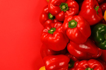 Fresh red, yelow, green bell pepper on a red background.