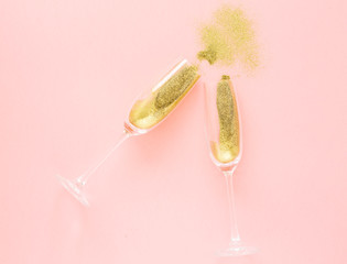 Champagne glasses with gold confetti on pink background. Happy New Year. Top view. The concept of celebration.  