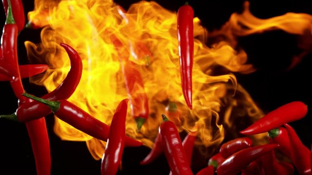 Super slow motion of flying red hot chilli peppers in fire with speed ramping effect. Filmed on high speed camera, 1000 fps