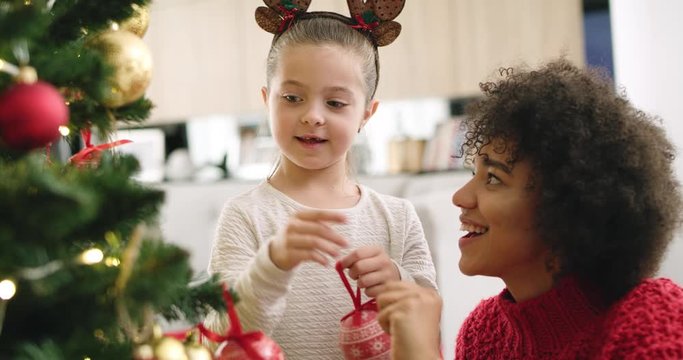 Handheld view of girl and mommy decorating the Christmas tree 