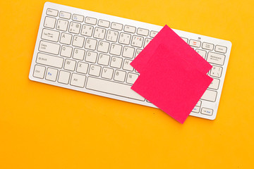 red sticky note and keyboard on orange background