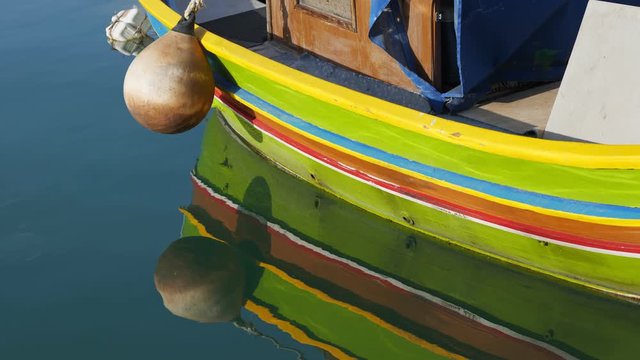 Traditional Maltese painted fishing boat called Luzzu with reflection in water in Marsaxlokk fishing village in Malta island on Mediterranean Sea