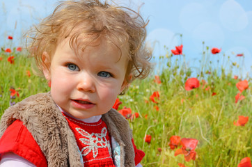pretty little girl playing in a field of poppies in bloom
