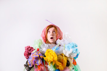 Emotional redhead woman looking stressed, covered with eco harmful plastic garbage, bags and straws of different color. Zero waste concept. Sad female frowning, angry about littering.