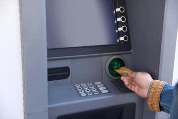 Young man using modern cash machine outdoors, closeup