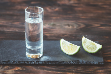 Glass of tequila with lime wedges