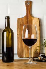 Botella de vino tinto y copa de vino vista de frente en la cocina