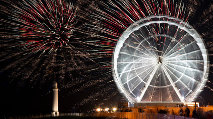 Fireworks exploding with a rotating ferris wheel