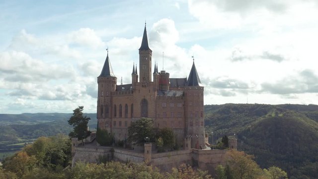 Aerial panorama of Burg Hohenzollern (Hohenzollern castle) with hills and villages surrounded by forests with beautiful foliage