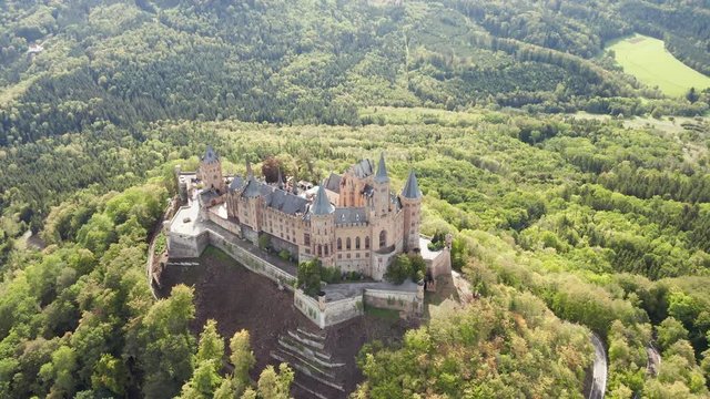 Aerial panorama of Burg Hohenzollern (Hohenzollern castle) with hills and villages surrounded by forests with beautiful foliage
