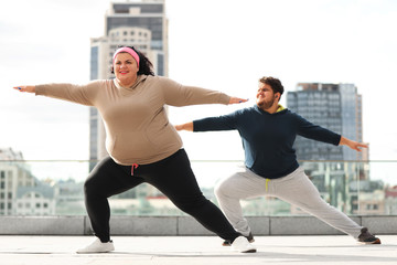 Overweight couple doing sport exercises together outdoors