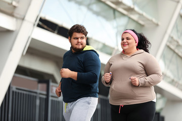 Fototapeta na wymiar Overweight couple running together outdoors. Fitness lifestyle