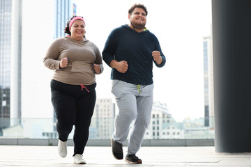 Overweight couple running together outdoors. Fitness lifestyle