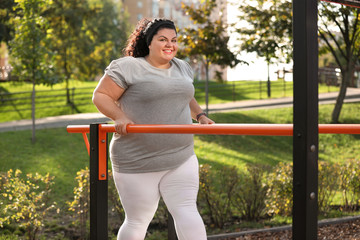 Beautiful overweight woman training on sports ground