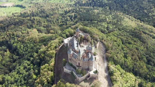 Aerial panorama of Burg Hohenzollern (Hohenzollern castle) with hills and villages surrounded by forests with beautiful foliage