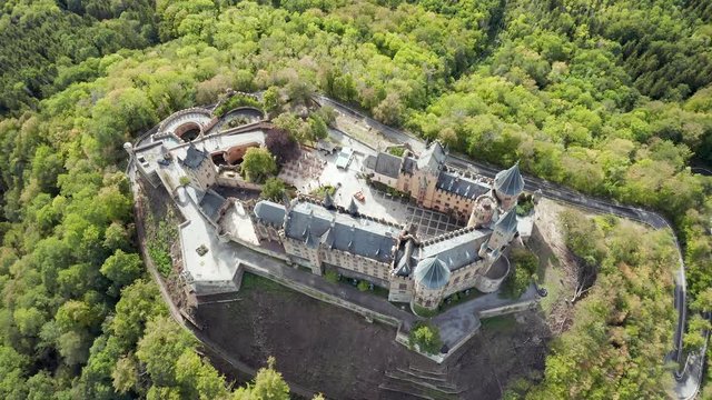 Aerial panorama of Burg Hohenzollern (Hohenzollern castle) with hills and villages surrounded by forests with beautiful foliage