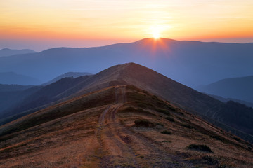 Autumn scenery. Mountain landscape with beautiful sunset, road, colorful horizon. Wonderful warm sunny morning. Wallpaper background. Touristic place Carpathian, Ukraine Europe.