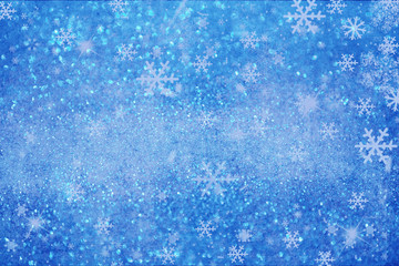 Christmas background with white blurred and clear snowflakes on light blue background.