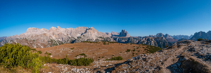 Fototapeta na wymiar Panoramic view of magical Dolomite peaks at the national park Three Peaks (Tre Cime, Drei Zinnen) in Autumn October colors during sunset at blue sky, South Tyrol, Italy