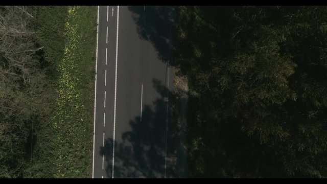 Moto pasando por carretera en plano cenital desde drone