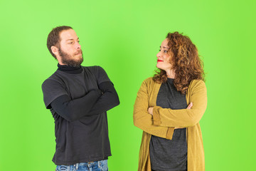 Beautiful young couple skeptic and nervous, disapproving expression on face with crossed arms over green background. Negative person.