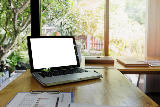 Laptop with blank screen on work table front view. Home interior or office background.